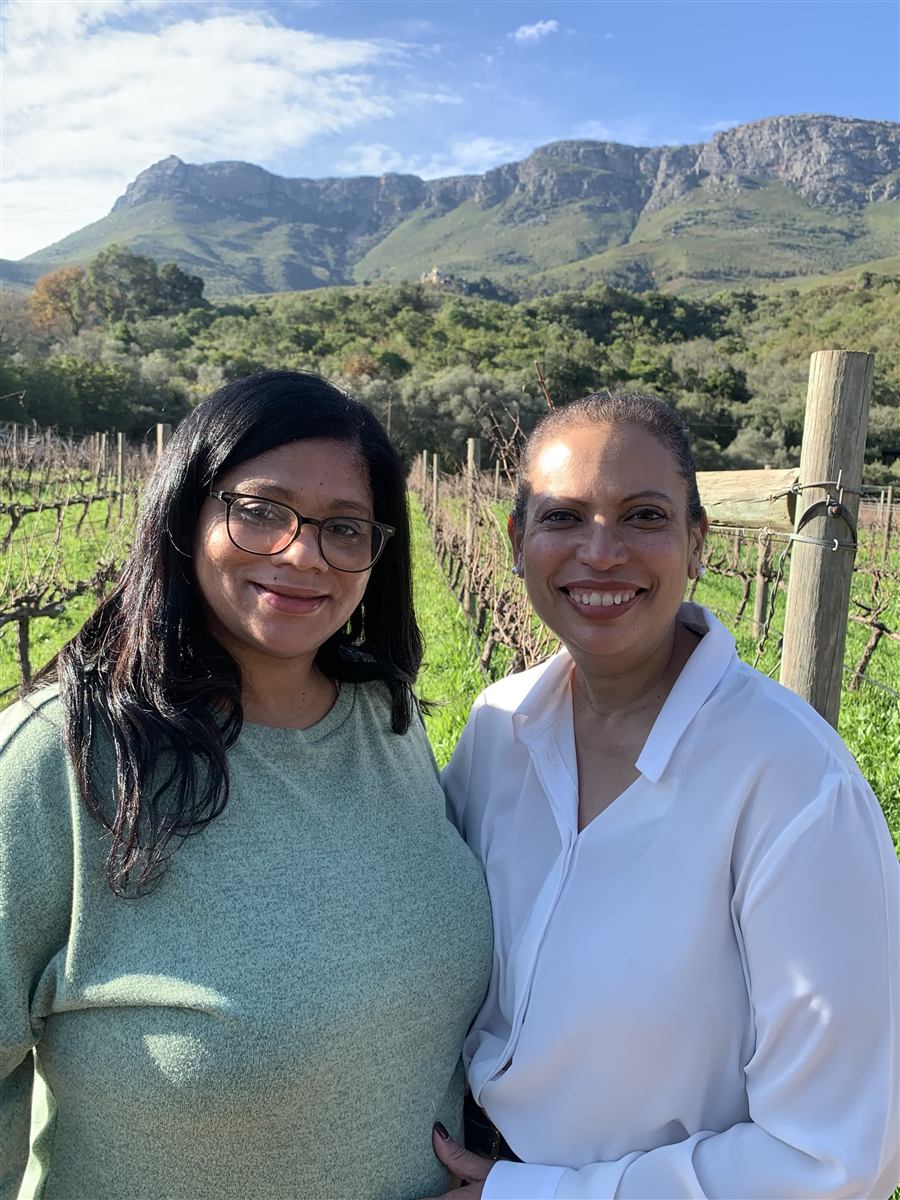 Leanie and Etherecia, founders of Furaha Escapes, standing together in a Cape Town vineyard with mountains behind them